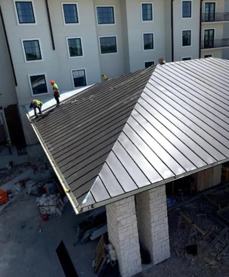 Crew installing standing seam metal roof panels on a commercial project in Schiller Park